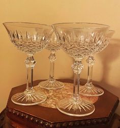 three clear wine glasses sitting on top of a wooden table in front of a wall