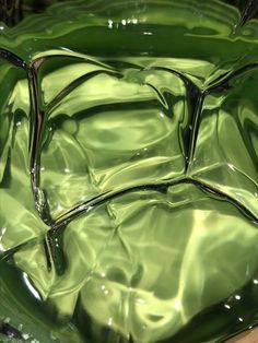 a green glass bowl sitting on top of a wooden table