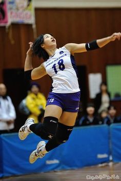 a woman jumping in the air to hit a volleyball