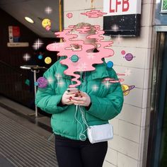 a woman standing in front of a building holding a cell phone and wearing headphones