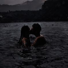 two people in the water at night, one is kissing the other's head