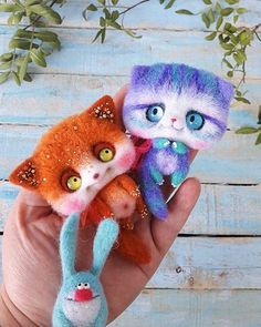 two small stuffed animals in the palm of someone's hand, one is orange and one is blue