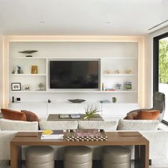 a living room filled with furniture and a flat screen tv mounted on the wall above it