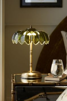 a table with a lamp on top of it next to a wine glass and book