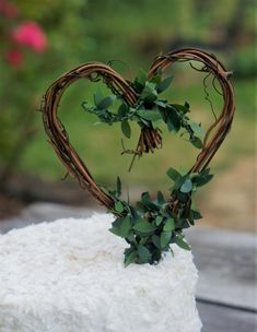 a heart shaped cake sitting on top of a wooden table next to a bushy plant