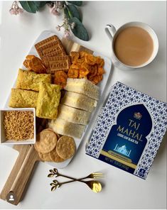 an assortment of food on a plate next to a cup of tea and some crackers