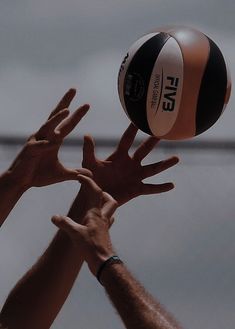 two hands reaching up to hit a volleyball