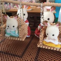 three little stuffed animals hanging from chains on a table