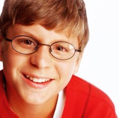 a young boy wearing glasses and smiling at the camera