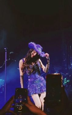 a woman in a purple dress and hat on stage