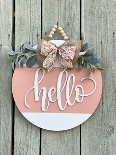 a sign that says hello on the side of a wooden fence with flowers and greenery