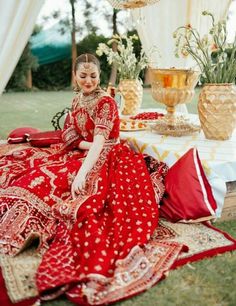 a woman sitting on top of a bed next to a table covered in red cloths