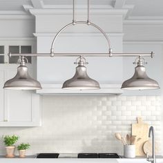 three lights are hanging over the kitchen counter