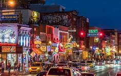 a city street filled with lots of traffic next to tall buildings and neon signs at night