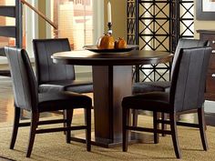 a dining room table with four chairs and a bowl of fruit on the top of it