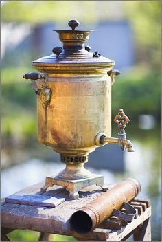 an old brass urn sitting on top of a wooden table next to a pipe