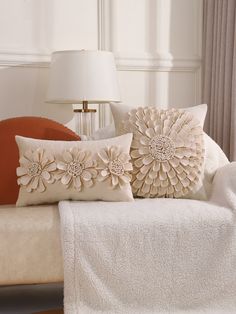 two decorative pillows sitting on top of a white couch