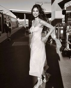 a woman in a white dress standing on a train platform