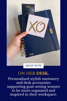 a person holding a notebook with the words, shop now on her desk