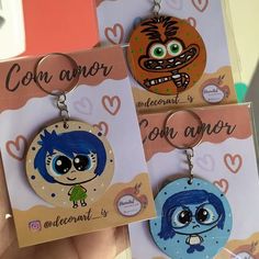 three key chains with cartoon characters hanging from it's sides in front of a card