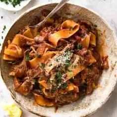 a white bowl filled with pasta and meat