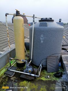 a large tank sitting on top of a roof next to a water heater and hose