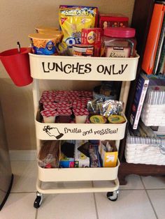 a cart with lunches on it sitting in front of a book shelf filled with books and snacks