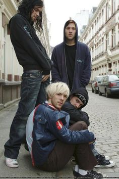 three young men standing next to each other on a street