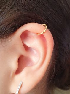 a close up of a person's ear with a gold ring on top of it