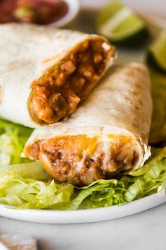 two burritos on a plate with lettuce and salsa