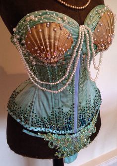 a mannequin with pearls and beads on it's bust, wearing a green corset