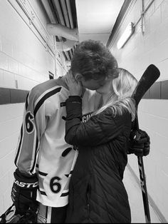 a man and woman are kissing in the locker room with baseball bats on their shoulders