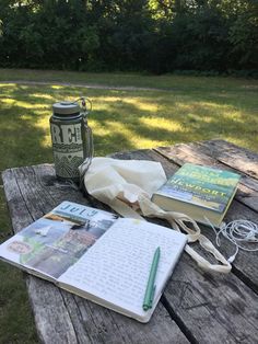 an open book sitting on top of a wooden table next to a notebook and pen