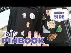 a woman's hand holding onto a piece of luggage with disney pins on it