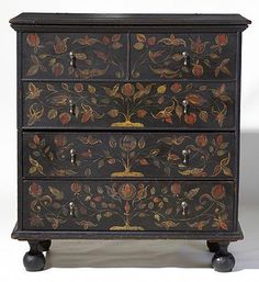 an ornate black painted chest of drawers with flowers and leaves on the front, one drawer open