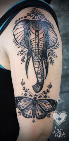 an elephant and butterfly tattoo on the back of a woman's shoulder with flowers