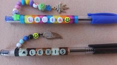 three pens are lined up next to each other on a table with beads and charms