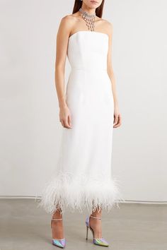 a woman wearing a white dress with feathers on it