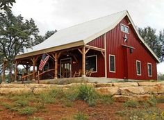 a red barn with an american flag on the front porch and covered in stone steps