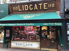 a store front with green awnings and gold lettering on the side of it