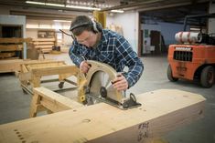 a man using a circular saw to cut planks in a shop with other woodworking equipment