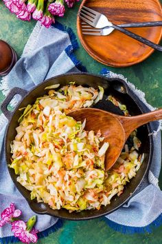 a skillet filled with coleslaw and wooden spoons