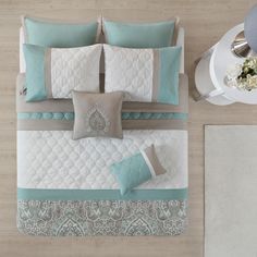 an aerial view of a bed with blue and white comforters, pillows and blankets