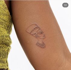 a woman's arm with a tattoo on it that has an egyptian mask on it