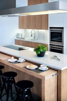 modern kitchen with white countertops and wooden cabinets, black bar stools in foreground