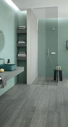 a bathroom with green walls and wood flooring in the shower area, along with a blue bathtub