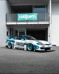 a white and blue sports car parked in front of a building with the word rollform on it's side