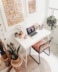 a white desk with a laptop on top of it next to two potted plants