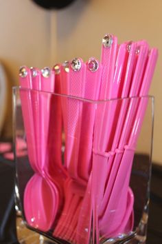 pink utensils in a clear container on a table