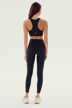 a woman in black sports bra top and leggings looking back at the camera